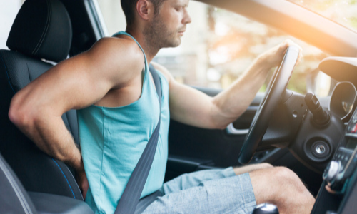 Man having back pain while driving car