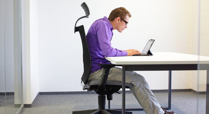 Young man hunched over laptop